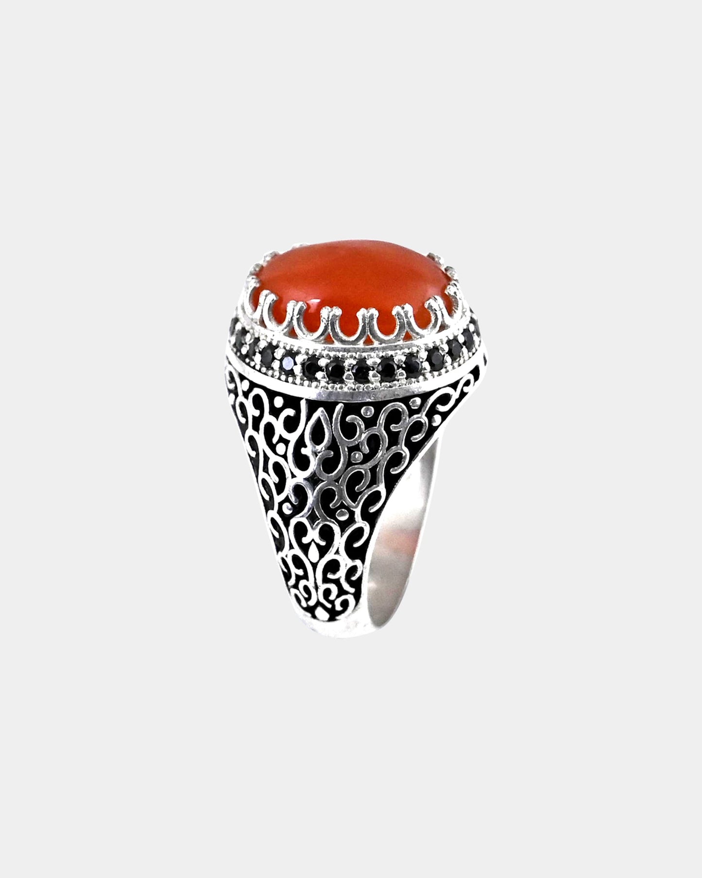 Decorative ring with a red stone and black gemstones on a white background