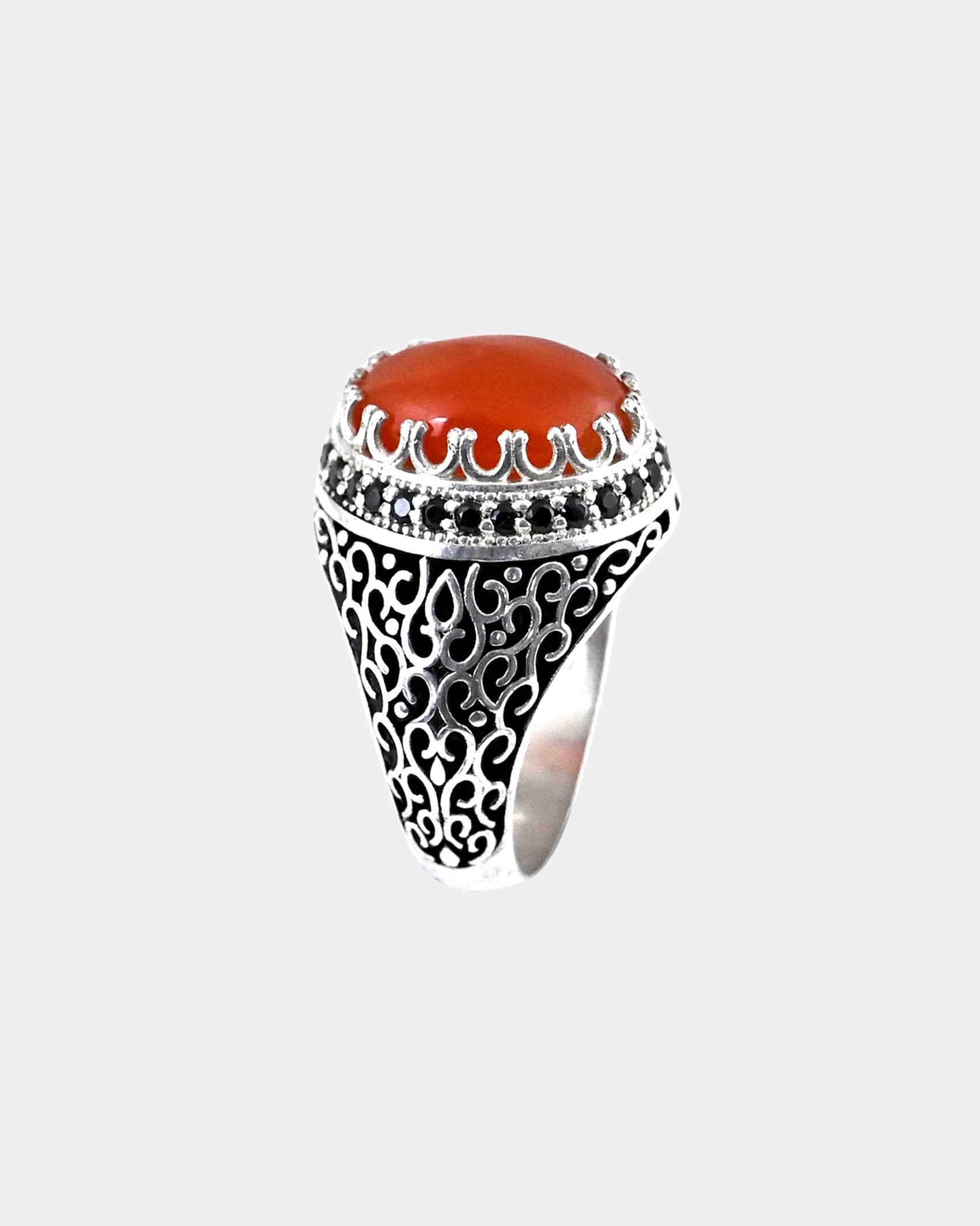 Decorative ring with a red stone and black gemstones on a white background