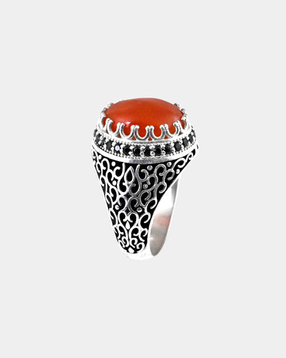 Decorative ring with a red stone and black gemstones on a white background